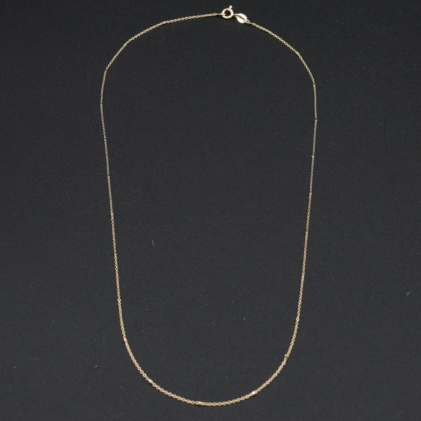 Collana in oro 18 carati con dettagli geometrici eleganti, design raffinato con piccoli quadrati distribuiti lungo la lunghezza per un tocco sofisticato.